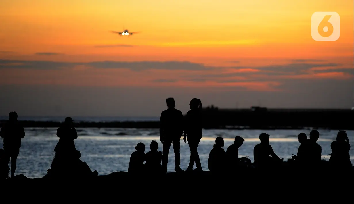 Wisatawan lokal beraktivitas di pantai yang surut dengan latar belakang pesawat di Pantai Kelan, Badung, Bali, Sabtu (22/4/2023). (merdeka.com/Arie Basuki)