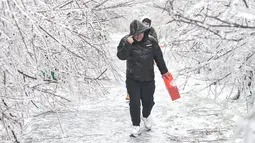 Para pejalan kaki berjalan melewati pepohonan yang tertutup es di Changchun, Provinsi Jilin, China timur laut, pada 19 November 2020. Hujan lebat dan salju yang jarang terjadi disertai angin kencang melanda Changchun pada 18 dan 19 November. (Xinhua/Xu Chang)