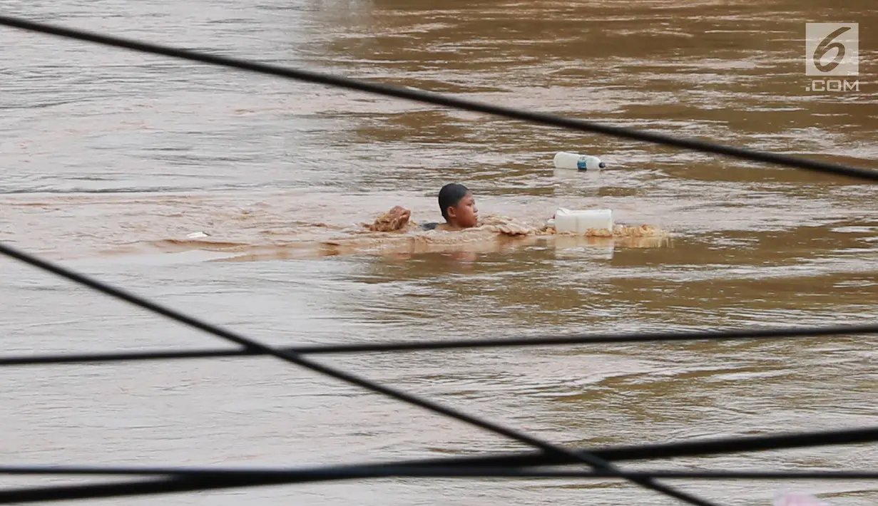 Seorang anak berenang di Sungai Ciliwung yang meluap di kawasan Rawajati, Jakarta, Jumat (26/4). Tingginya volume debit air yang berasal dari Bogor tidak menyurutkan niat anak-anak itu untuk tetap berenang, meskipun berbahaya bagi keselamatan. (Liputan6.com/Immanuel Antonius)