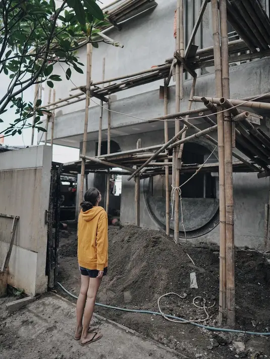Sabai Morschek tampak mengamati rumahnya yang sedang di renovasi. Tampak, beberapa bambu masih berdiri sebagai tangga.  Sedangkan pasir juga terlihat masih banyak. [Instagram/ringgoagus]