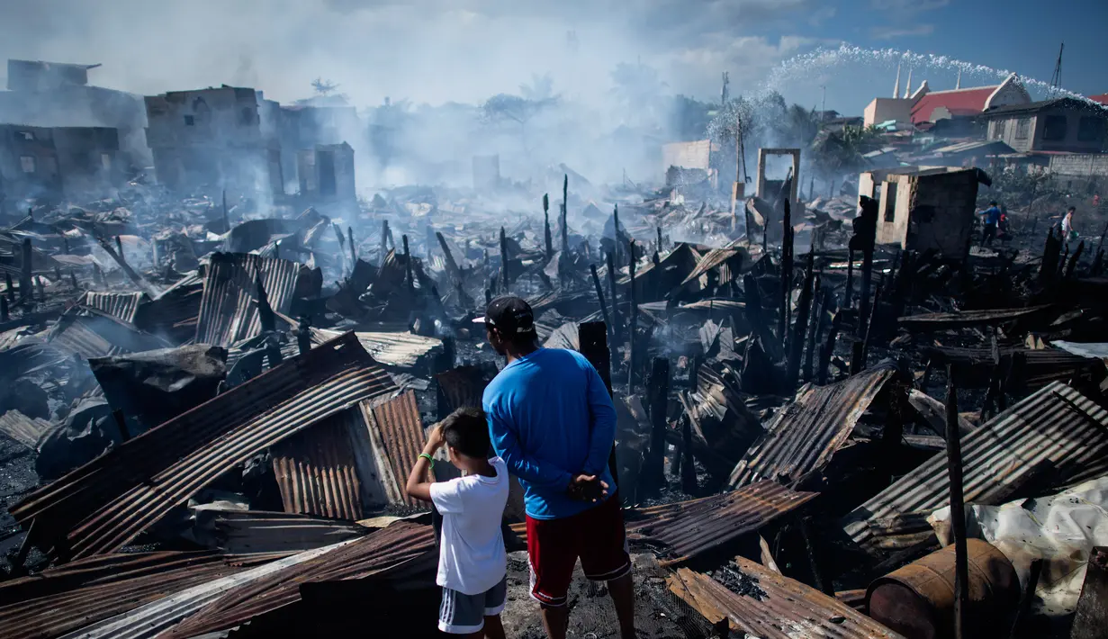 Warga melihat rumah-rumah mereka hangus terbakar di sebuah daerah kumuh di Navotas, Manila (8/11). Dilaporkan sekitar 150 keluarga terkena dampak kebakaran tersebut. (AFP Photo/Noel Celis)