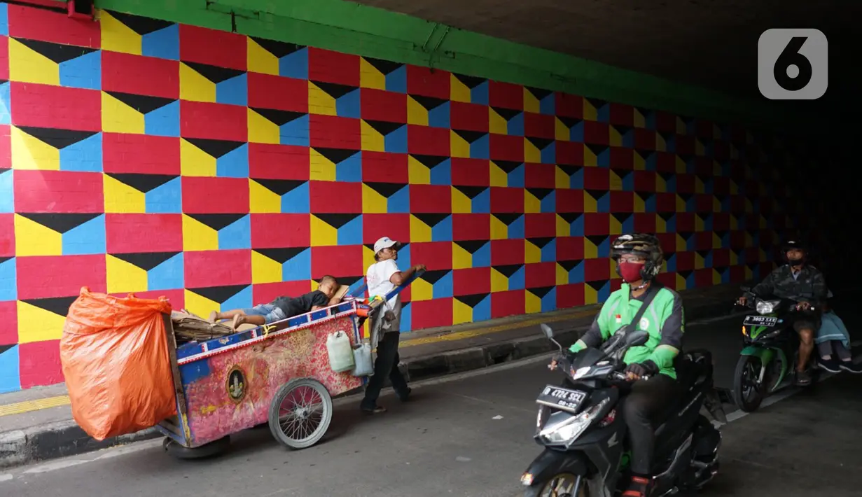 Pengguna jalan melintasi tembok kolong jembatan Stasiun Kereta Api Cawang yang dihiasi mural bernuansa kemerdekaan di Jakarta, Rabu (12/8/2020). Pembuatan mural di lokasi dilakukan dalam rangka menyambut Hari Ulang Tahun (HUT) ke-75 Kemerdekaan RI. (Liputan6.com/Immanuel Antonius)