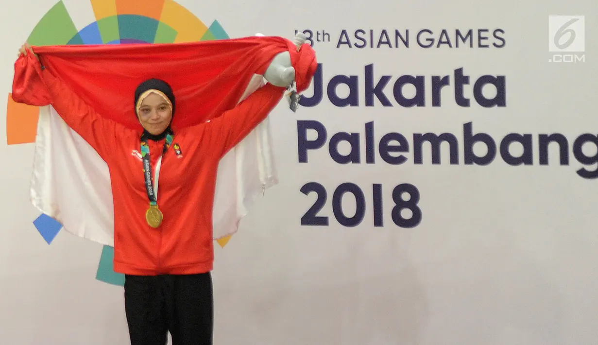 Pesilat Indonesia Sarah Tria Monita mengangkat bendera Merah Putih usai menaklukkan Nong Oy Vongphakdy asal Laos dalam babak final Kelas C Putri Asian Games 2018 di Jakarta, Senin (27/8). Sarah menang dan mendapatkan medali emas. (Merdeka.com/Arie Basuki)