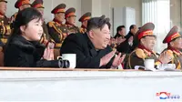 Pemimpin Korea Utara Kim Jong Un dan putrinya Kim Ju-ae bertepuk tangan saat menyaksikan pertandingan sepak bola antara staf Kabinet dan Kementerian Pertahanan Nasional, di Korea Utara pada 17 Februari 2023. Kim Jong Un mengajak putrinya dalam rangka merayakan ulang tahun kakeknya Kim Jong Il menandai penampilan pertama gadis itu yang tidak secara terbuka terkait dengan nuklir. (AFP/KCNA Via KNS)