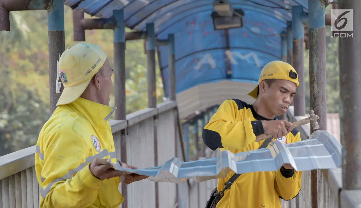 Petugas memerbaiki atap JPO di sekitar kawasan Lenteng Agung, Jakarta, Selasa (28/8). Hal itu dilakukan guna memberikan kenyamanan bagi pengguna JPO, mengingat banyak bagian dari JPO tersebut yang telah keropos dan rusak. (Liputan6.com/Immanuel Antonius)
