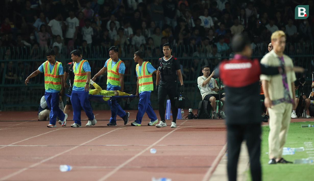 <p>Kiper Timnas Indonesia U-22, Muhammad Adisatryo ditandu ke luar lapangan setelah mengalami cedera usai menepis eksekusi tendangan penalti pemain Kamboja pada laga keempat Grup A SEA Games 2023 di Olympic National Stadium, Phnom Penh, Kamboja, Rabu (10/5/2023). (Bola.com/Abdul Aziz)</p>