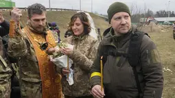 Seorang pendeta militer memimpin upacara pernikahan anggota Pasukan Pertahanan Teritorial Ukraina Lesia Ivashchenko dan Valerii Fylymonov (kanan) pada upacara pernikahan di pos pemeriksaan di Kiev, 6 Maret 2022. Kedunya menikah dengan upacara seadanya yang dilakukan korps mereka. (AP/Efrem Lukatsky)