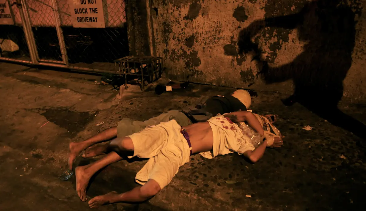 Dua jenazah pria dengan kondisi kepala terbungkus lakban di pinggir jalan Kota Pasay, Filipina (15/11). Filipina terus membasmi peredaran narkoba dengan cara menembak di tempat bagi pecandu dan pengedar narkoba. (Reuters/Romeo Ranoco)
