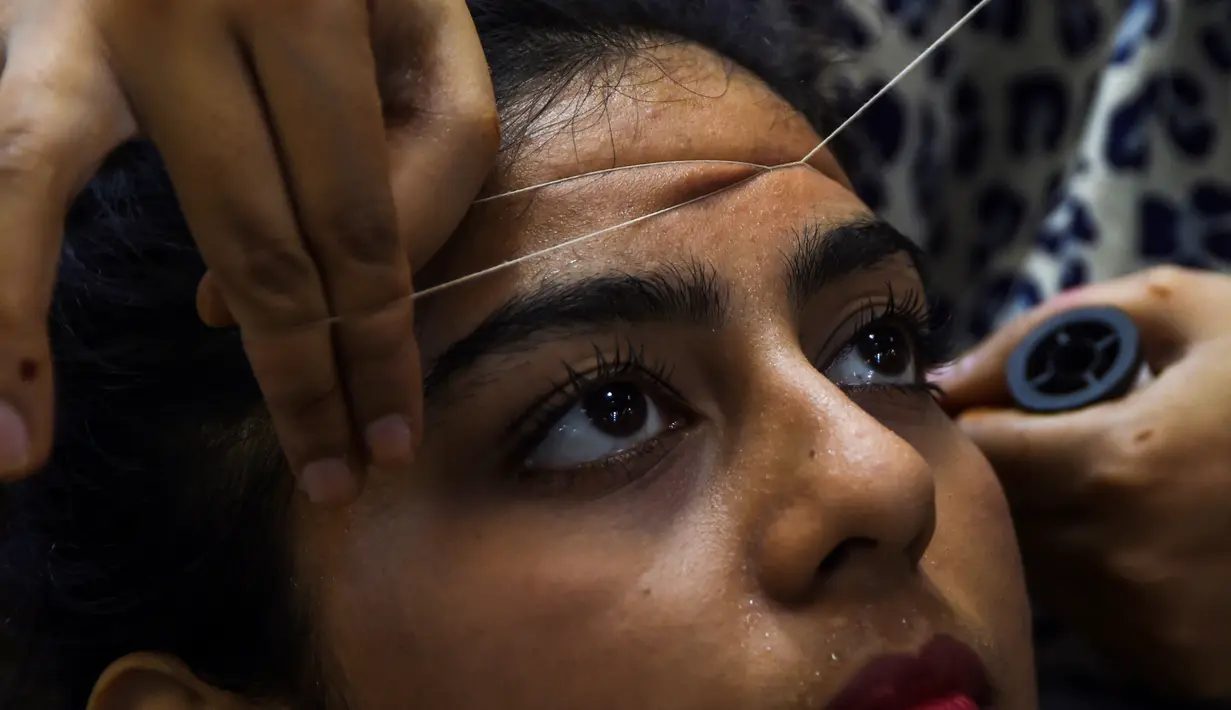 Seorang wanita Pakistan membersihkan rambut di wajah di salon kecantikan menjelang  Hari Raya Idul Fitri di Karachi (3/6/2019). Umat Muslim di seluruh dunia sedang bersiap untuk merayakan Hari Raya Idul Fitri, yang menandai akhir bulan puasa Ramadan. (AFP Photo/Asif Hassan)