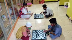 Anak-anak bermain catur di Rumah Amalia, Kota Tangerang, Selasa (23/03/2021). Kegiatan mengisi waktu usai belajar daring ini bisa mengasah ketelitian,fokus dan juga strategi dalam permainan selama masa pandemi Covid-19. (Liputan6.com/Fery Pradolo)