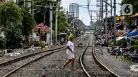 Seorang wanita melintasi rel kereta di kawasan pemukiman padat Pejompongan di tengah pandemi COVID-19, Jakarta, Kamis (28/1/2020). Sensus Penduduk 2020 (SP2020) mencatat penduduk DKI Jakarta pada bulan September 2020 sebanyak 10,56 juta  jiwa. (Liputan6.com/Johan Tallo)