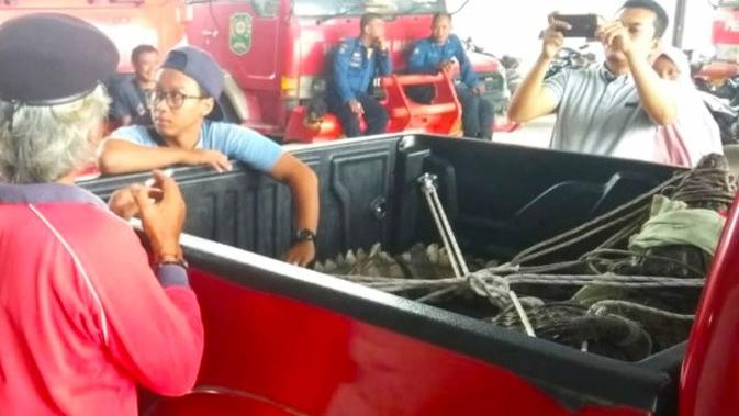 Petugas Damkar mengevakuasi buaya muara yang masuk perkampungan dan berjemur di Siak. (Liputan6.com/Dok BBKSDA Riau/M Syukur)