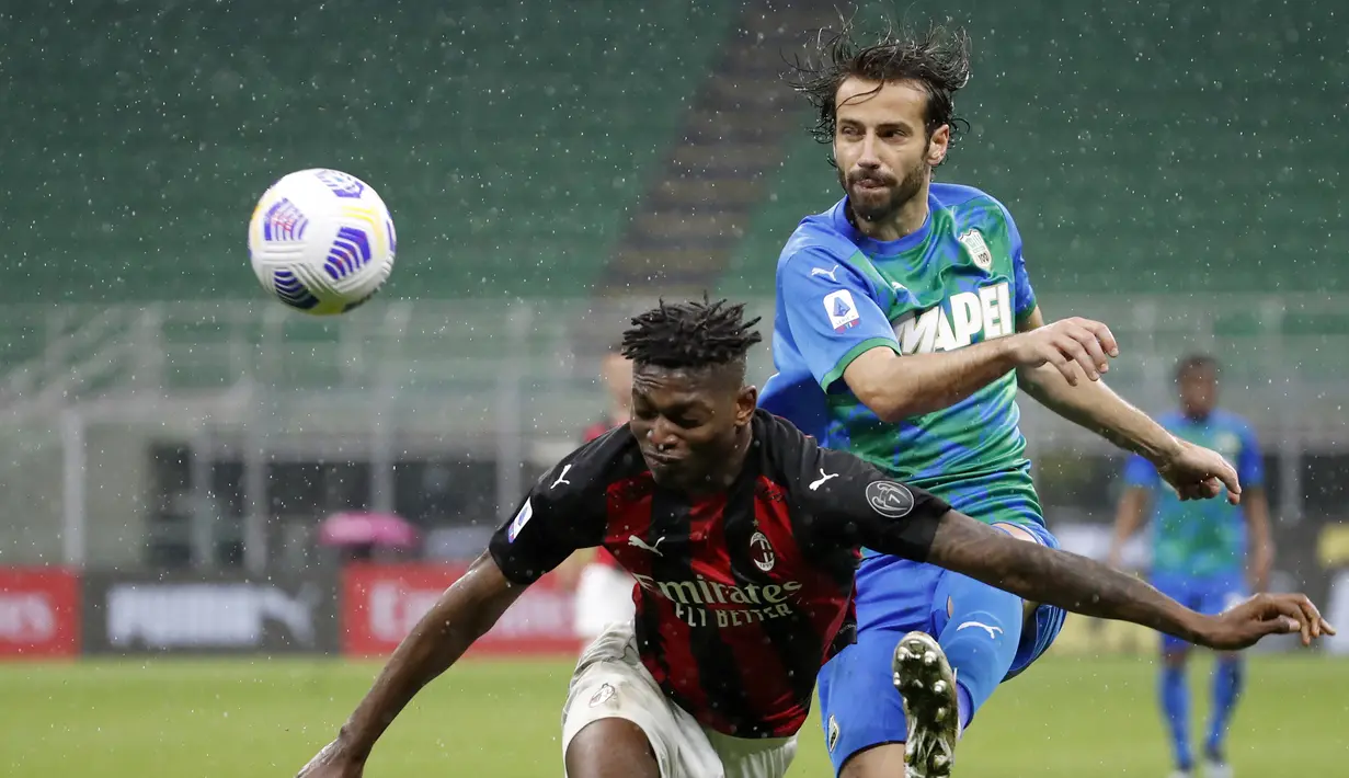 Striker AC Milan, Rafael Leao (kiri) berebut bola dengan bek Sassuolo, Gian Marco Ferrari dalam laga lanjutan Liga Italia 2020/2021 pekan ke-32 di San Siro Stadium, Milan, Rabu (21/4/2021). AC Milan kalah 1-2 dari Sassuolo. (AP/Antonio Calanni)