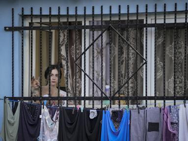 Seorang wanita menyaksikan pemutaran film bertema kekerasan aparat, dalam sebuah festival 'outdoor' di Bucharest, Rumania (31/8/2021). International Roma Theatre Festival digelar di permukiman warga ekonomi rendah. (AP Photo/ Vadim Ghirda)