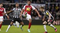 Penyerang Newcastle United Callum Wilson berebut bola dengan bek Arsenal William Saliba pada laga Premier League 2023/2024 pekan 11 yang digelar di St. James' Park, Minggu (5/11/2023) dini hari WIB. (Owen Humphreys/PA via AP)