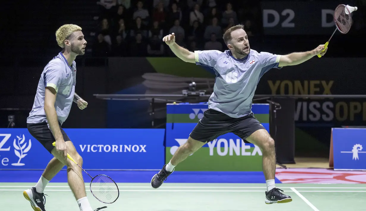 Pemain ganda putra Inggris, Ben Lane (kanan) yang berpasangan dengan Sean Vendy berusaha memotong bola pengembalian ganda putra Indonesia, Muhammad Shohibul Fikri/Bagas Maulana pada laga final kejuaraan bulu tangkis Swiss Open 2024 di St. Jakobshalle, Basel, Swiss, Minggu (24/3/2024). Ben Lane/Sean Vendy menang dua gim langsung 24-22, 28-26 untuk menjadi juara. (Keystone via AP Photo/Georgios Kefalas)
