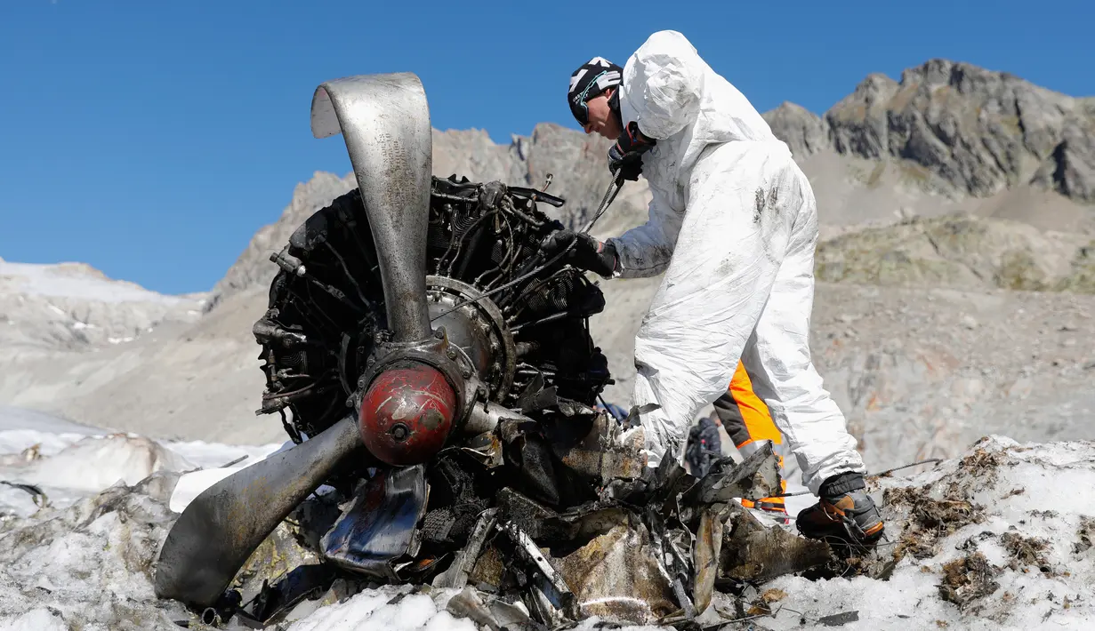 Anggota tentara Swiss mengecek mesin pesawat tempur Perang Dunia II milik AS saat ditemukan di Gauli Glacier, di Bernese Alps, Swiss (17/9). Pesawat Perang Dunia II C-53 Skytrooper Dakota tersebut jatuh tahun 1946. (Peter Klaunzer/Keystone via AP)