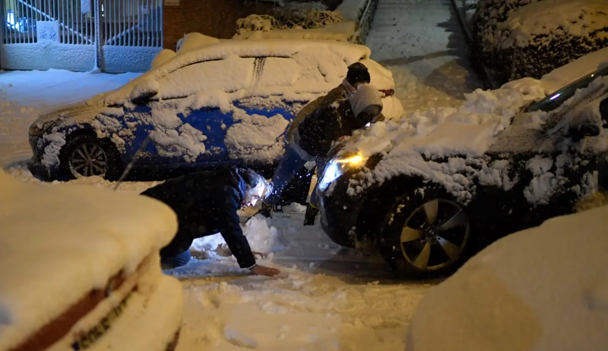 Seorang pria terjatuh saat mendorong mobil yang terjebak salju tebal di Madrid, Spanyol, Jumat (8/1/2021). Badai Filomena mengakibatkan salju lebat turun di Madrid dan sebagian besar wilayah Spanyol. (OSCAR DEL POZO/AFP)
