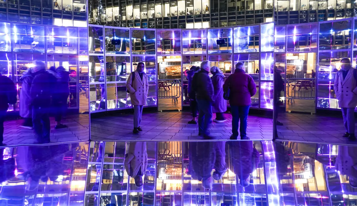 Orang-orang memotret "Emergence" oleh This Is Loop, sebagai bagian dari festival Winter Lights di Canary Wharf, di London, Rabu (18/1/2023). Festival Winter Lights kembali ke Canary Wharf untuk pertama kalinya sejak 2020. (AP Photo/Alberto Pezzali)