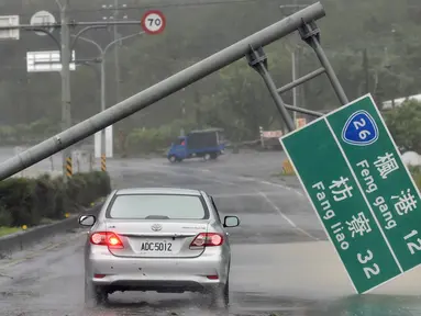 Mobil melewati papan penunjuk jalan yang ambruk akibat hantaman topan super Meranti di  Taiwan selatan, Rabu (14/9). Sejumlah kerusakan, seperti tiang listrik roboh dan banyaknya pohon tumbang dilaporkan terjadi akibat terjangan topan itu. (Sam YEH/AFP)