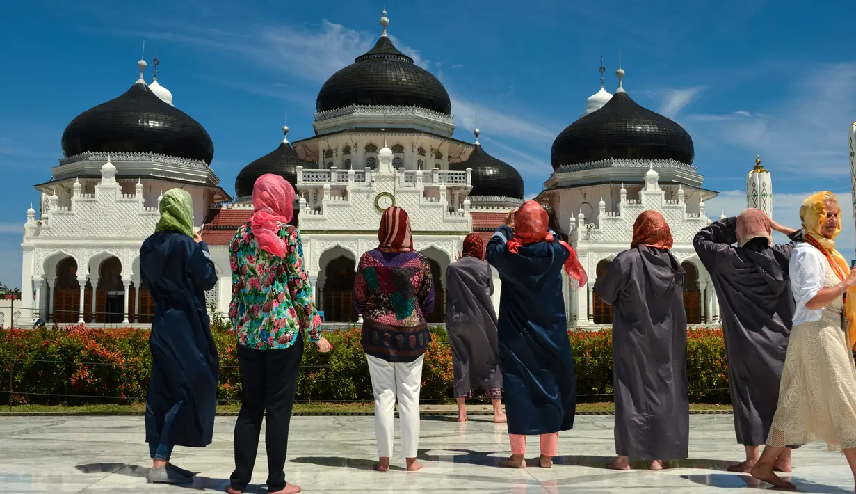 Turis asing dengan mengenakan kerudung mengambil gambar Masjid Agung Baiturrahman di Banda Aceh, Aceh pada 6 Agustus 2019. Selain sebagai tempat ibadah, Masjid Baiturahman juga menjadi tempat wisata bagi turis lokal dan mancanegara. (CHAIDEER MAHYUDDIN / AFP)