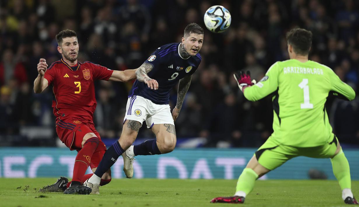 Pemain Skotlandia, Lyndon Dykes (tengah) berusaha mencetak gol ke gawang Spanyol yang dijaga David Garcia pada matchday kedua Kualifikasi Euro 2024 di Hampden Park, Glasgow, Skotlandia, Rabu (29/03/2023) WIB. Skotlandia berhasil menang dengan skor 2-0. (AP Photo/Scott Heppell)
