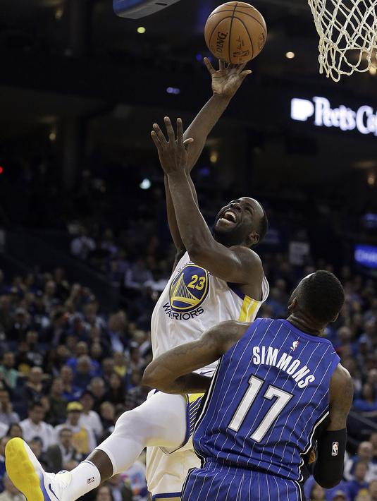 Pemain Warriors, Draymond Green (kiri) melakukan lay up melewati adangan pemain Orlando Magic, Jonathon Simmons (17) pada lanjutan NBA Basketball game di Oracle Arena, Oakland, (13/11/2017). Warriors menang 110-100. (AP/Ben Margot)
