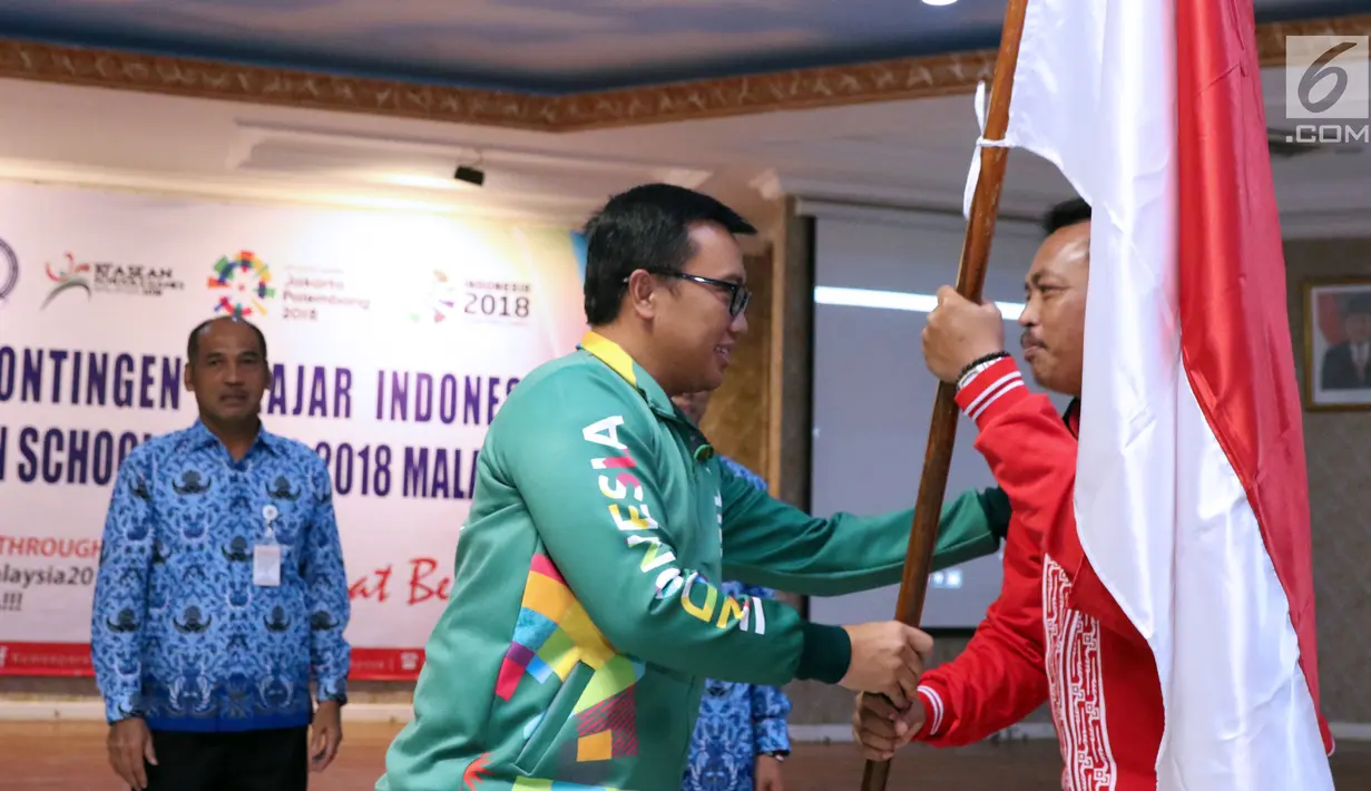 Menpora, Imam Nahrawi (tengah) memberi bendera Merah Putih pada CdM Asian School Games 2018, Bambang Siswanto usai pelepasan di Jakarta, Selasa (17/7). 158 atlet pelajar Indonesia akan bertanding di delapan cabang orang. (Liputan6.com/Helmi Fithriansyah)