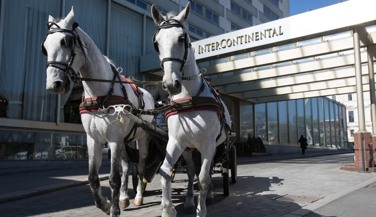 Pengemudi mengendarai kereta kuda di depan Hotel Intercontinental di distrik ke-3 di Wina, Austria pada 8 April 2020. Kereta yang disebut Fiaker yang biasanya mengangkut turis semenjak pandemi Corona beralih fungsi menjadi pengantar makanan untuk lanjut usia di daerah tersebut. (ALEX HALADA/AFP)