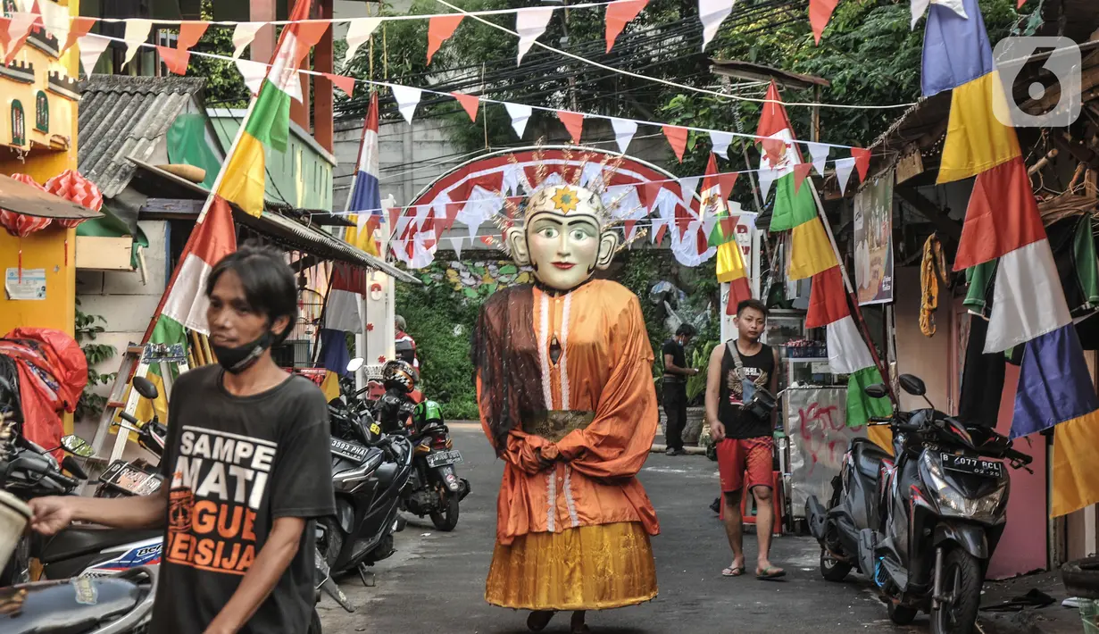 Pengamen ondel-ondel saat melintas di "Kampung Merdeka" RW 04 Kelurahan Kebon Melati, Tanah Abang, Jakarta, Rabu (11/8/2021). Warga setempat menyulap permukiman padat yang berada di antara gedung bertingkat itu menjadi "Kampung Merdeka". (merdeka.com/Iqbal S Nugroho)