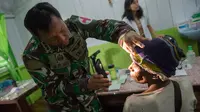 Tim medis dari satuan tugas militer Indonesia memeriksa seorang pasien di rumah sakit setempat di Agats, Asmat, provinsi Papua Barat (26/1). (AFP/Bay Ismoyo)