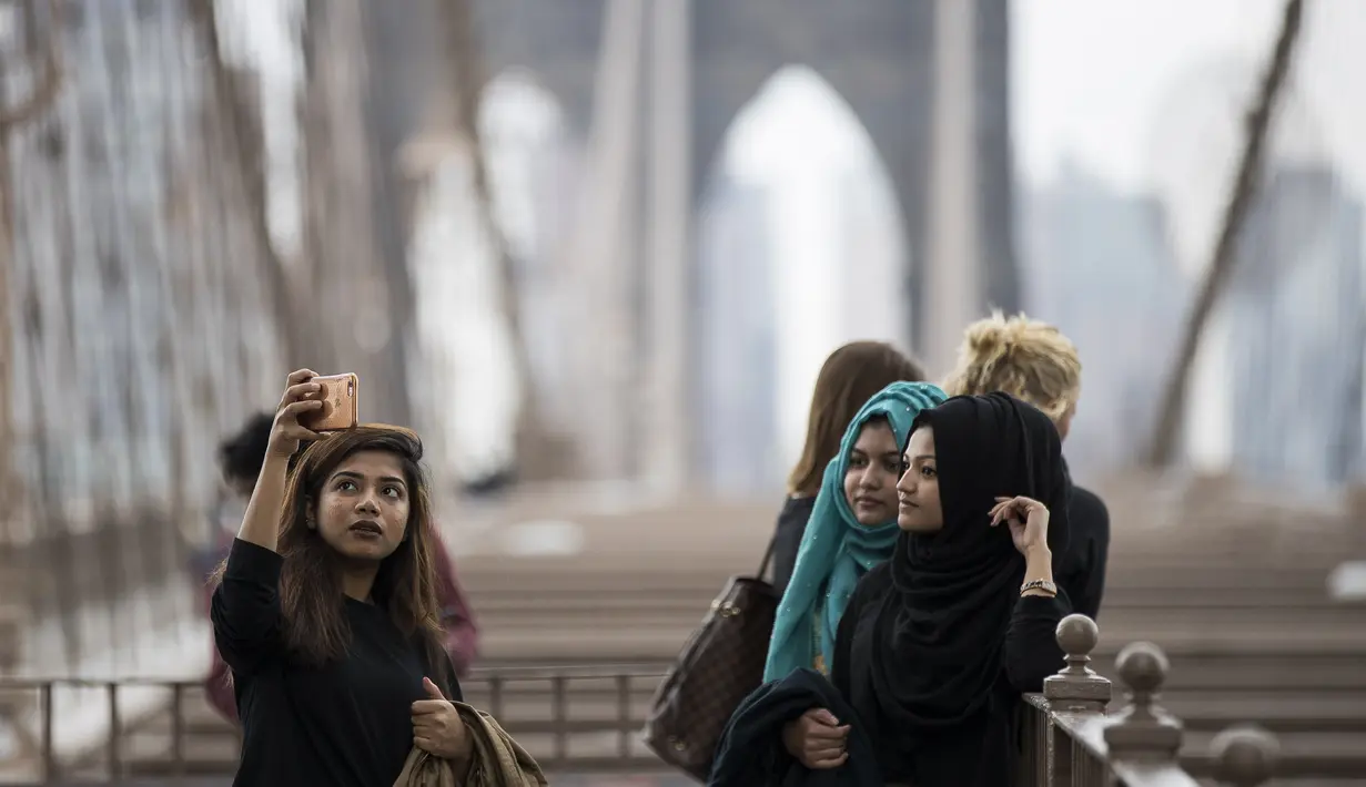 Turis berfoto di Jembatan Brooklyn, AS, Rabu (1/3). Wisatawan asing mulai mengunjungi Amerika Serikat (AS), setelah kebijakan imigrasi Presiden AS, Donald Trump ditolak mahkamah banding. (Drew Angerer / Getty Images / AFP)