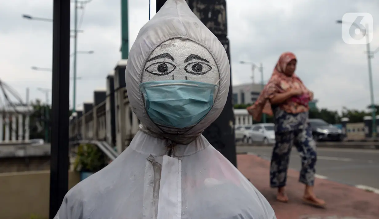 Patung bermasker terlihat di pinggiran Kali Kanal Barat, Cakung, Jakarta, Kamis (25/2/2021). Pemerintah terus berupaya mengampanyekan penggunaan masker kepada masyarakat di tengah kasus virus corona COVID-19 yang terus meningkat. (merdeka.com/Imam Buhori)