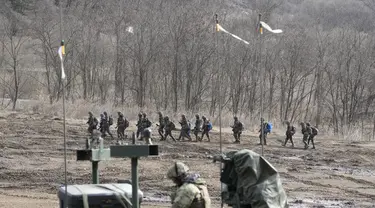 Tentara Korea Selatan berbaris ketika seorang tentara AS duduk di kendaraan militer selama latihan militer bersama di Paju, Korea Selatan, Kamis, 16 Maret 2023. (AP Photo/Lee Jin-man)