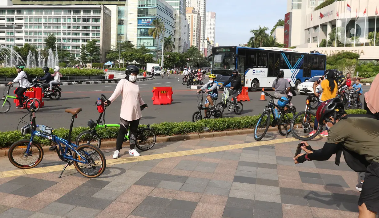 Seorang wanita berpose dengan sepedanya di kawasan Bundaran HI, Jakarta, Minggu (3/01/2021). Sejumlah aktivitas pesepeda melintasi jalan sudirman-thamrin di minggu pertama 2021, meski Car Free Day saat ini belum diberlakukan karena PSBB. (Liputan6.com/Herman Zakharia)