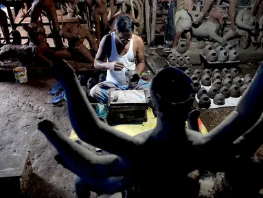 Seorang perajin mengerjakan wajah patung tanah liat dewi Hindu Durga di sebuah lokakarya menjelang festival Durga Puja di Vashi di Navi Mumbai (23/9/2021). Durga Puja  adalah festival tahunan di Asia Selatan untuk memuja dewi Durga dari agama Hindu. (AFP/Indranil Mukherjee)