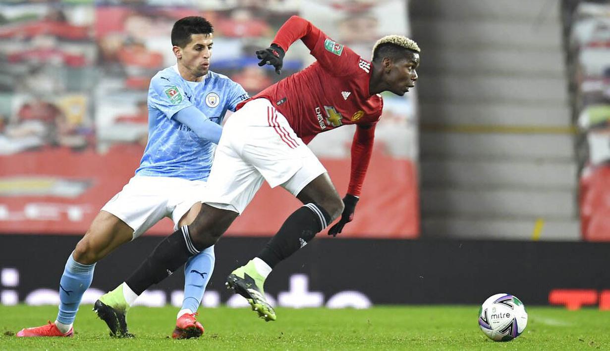 Bek Manchester City, Joao Cancelo, berebut bola dengan pemain Manchester United, Paul Pogba, pada laga Piala Liga Inggris di Stadion Old Trafford, Rabu (6/1/2021). City menang dengan skor 2-0. (Peter Powell/Pool via AP)