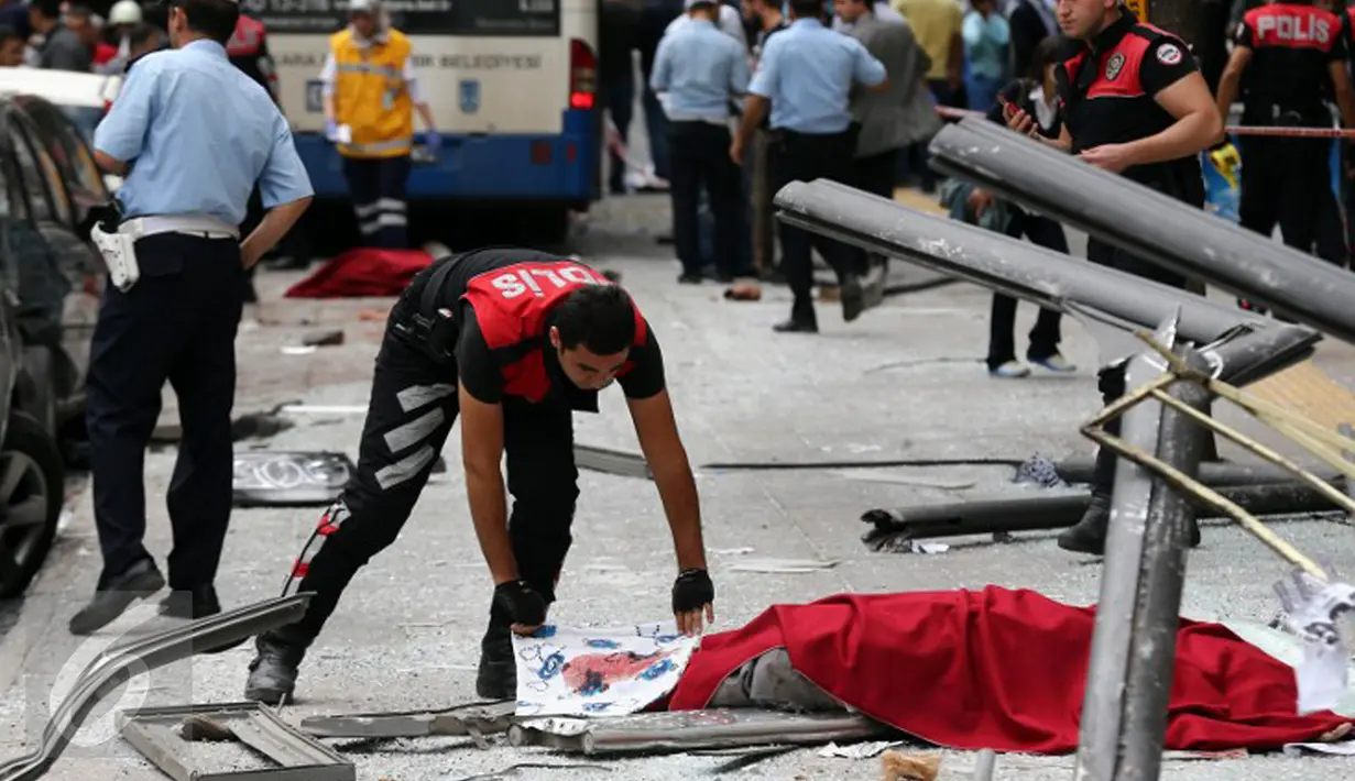 Polisi menutupi tubuh jenazah korban tewas akibat sebuah bus menabrak halte yang penuh penumpang di distrik Dikimevi, Ankara, Turki, Kamis (1/10/2015). 12 orang tewas akibat bus kehilangan kendali karena mengalami rem blong. (AFP PHOTO/ADEM ALTAN)