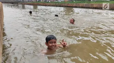 Anak-anak berenang di Sungai Kalimalang, Jakarta Timur, Jumat (5/7/2019). Tingginya suhu udara Ibu Kota akibat musim kemarau menyebabkan anak-anak tersebut berenang di Sungai Kalimalang meski dengan kondisi seadanya. (Liputan6.com/Immanuel Antonius)