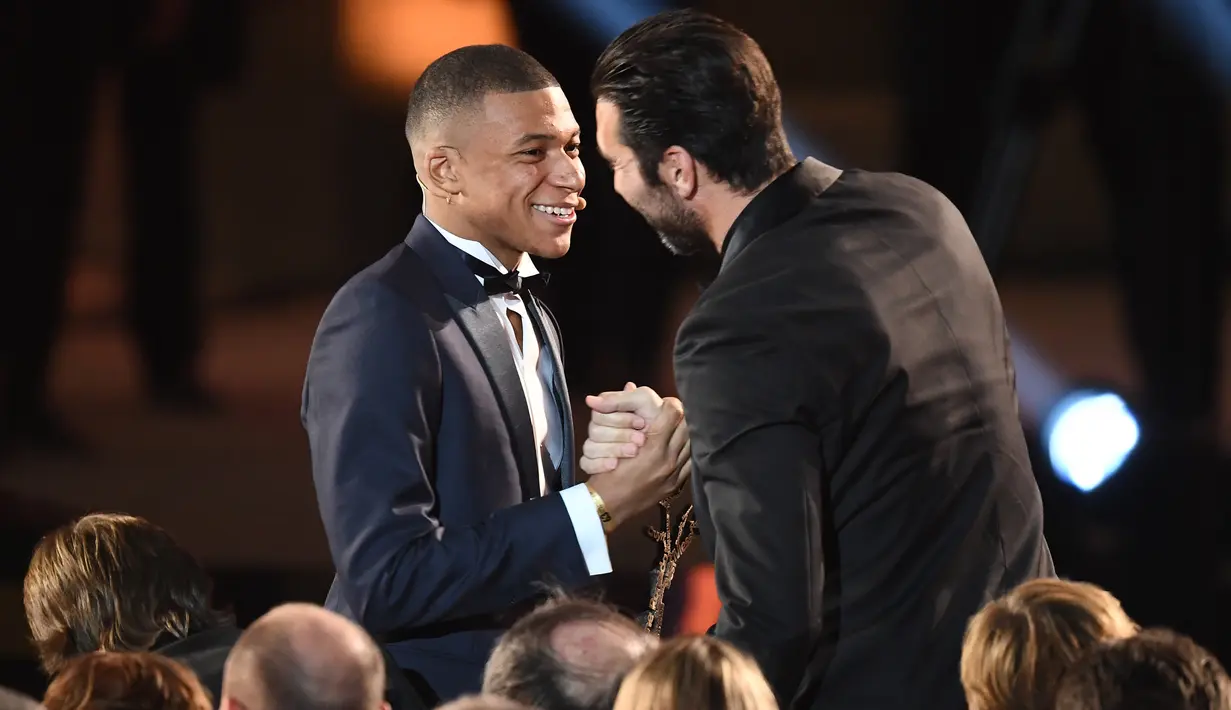 Striker Paris Saint-Germain, Kylian Mbappe mendapat ucapan selamat dari rekannya, Gianluigi Buffon setelah menerima penghargaan Trophee Kopa pada seremoni Ballon d'Or 2018 di Grand Palais, Senin (3/12). (FRANCK FIFE/AFP)