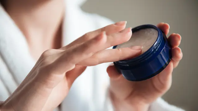 Seorang perempuan sedang mengoles parfum solid menggunakan jarinya (Foto Dok: Freepik/drobotdean)