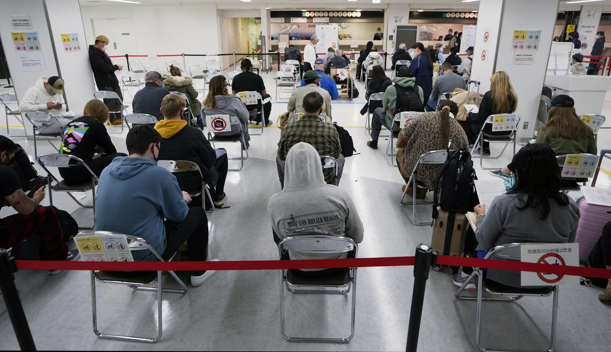 Penumpang duduk dan menunggu giliran selama proses karantina pencegahan virus corona setelah mendarat di Bandara Internasional Narita di Narita, timur Tokyo, Jepang (2/12/2021). (AP Photo/Hiro Komae)