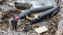 Seorang pria berdiri di samping perahu karet di Thermi di pulau Lesbos Yunani pada 7 Februari 2023. Tiga migran tewas dan lebih dari 20 orang dikhawatirkan hilang setelah perahu kedua tenggelam di lepas pantai Yunani hanya dalam beberapa hari, kata penjaga pantai. (Manolis Lagoutaris / AFP)