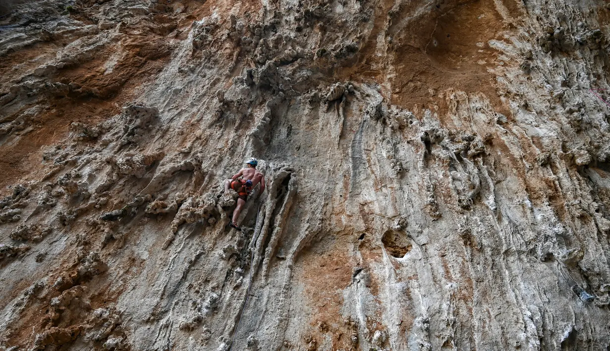 Peserta berusaha memanjat tebing dalam Festival Mendaki tahunan 2019 di pulau Kalymnos, Yunani (4/10/2019). Pemandangan menakjubkan dan cuaca bagus menjadikan pulau ini sebagai tujuan utama bagi pemanjat dari semua tingkatan dengan lebih dari 2500 rute pendakian. (AFP Photo/Aris Messinis)