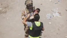 Tentara AS membawa seorang anak di pos pemeriksaan selama evakuasi di Bandara Internasional Hamid Karzai di Kabul, Jumat (20/8/2021). Sejumlah ibu Afghanistan berupaya menyerahkan bayi-bayi mereka pada tentara asing yang berjaga di bandara. (Staff Sgt. Victor Mancilla/U.S. Marine Corps via AP)