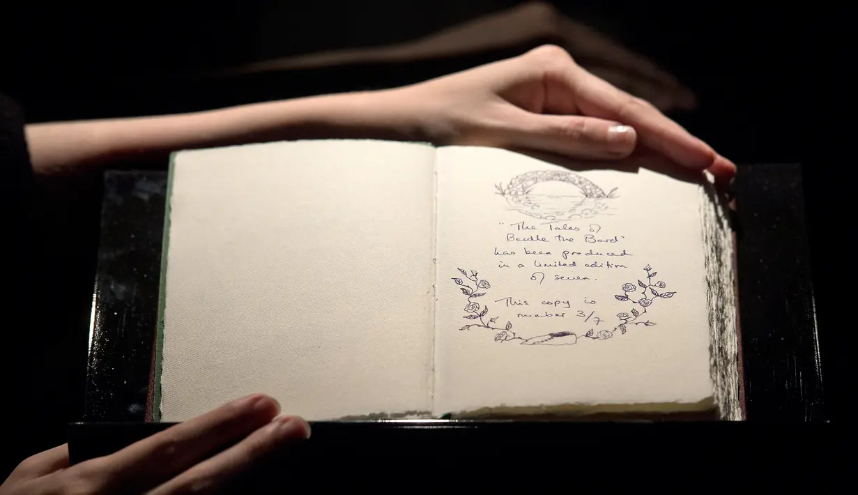 Pekerja memperlihatkan satu dari tujuh eksemplar buku tulisan tangan dan digambar oleh J.K. Rowling di rumah lelang Sotheby, London, 9 Desember 2016. Buku 'The Tales of Beedle the Bard' itu terjual USD467 ribu atau sekitar Rp6,2 miliar (Justin TALLIS/AFP)