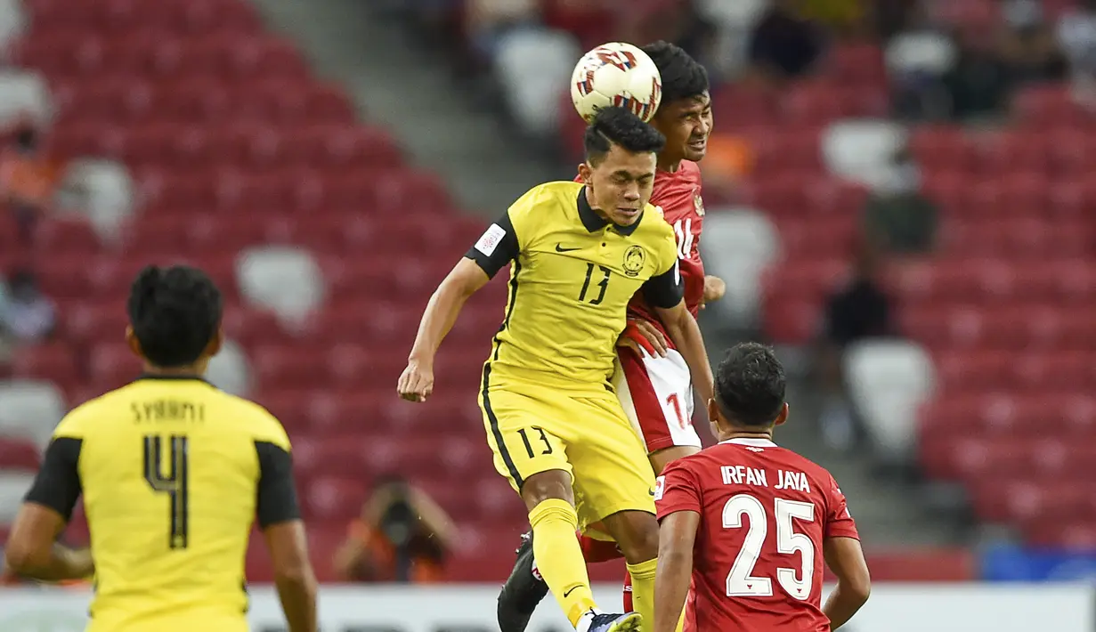 Bek Timnas Indonesia, Asnawi Mangkualam Bahar (kanan atas) berebut bola udara dengan gelandang timnas Malaysia, Arif Aiman pada laga Grup B Piala AFF 2020 di Stadion Nasional Singapura, Minggu (19/12/2021). timnas Indonesia menaklukkan Malaysia 4-1. (AFP/Roslan Rahman)