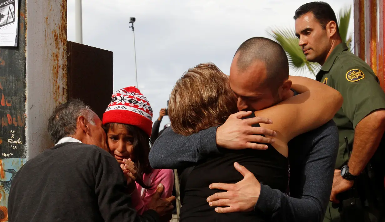 Seorang pria memeluk keluarganya di depan gerbang perbatasan Meksiko dan Amerika Serikat, Tijuana, Meksiko (19/11). Untuk memperingati Hari Anak Sedunia, petugas perbatasan membolehkan imigran Meksiko bertemu dengan keluarganya. (Reuters/Jorge Duenes)