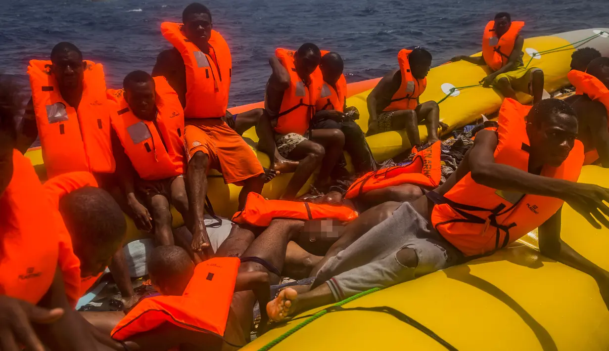 Sejumlah imigran menunggu di atas perahu karet untuk diselamatkan di lepas pantai Libya, Selasa (25/7). Kapal penyelamat kemanusiaan milik LSM asal Spanyol, Proactiva Open Arms, menemukan 13 jasad di atas perahu karet tersebut. (AP/Santi Palacios)