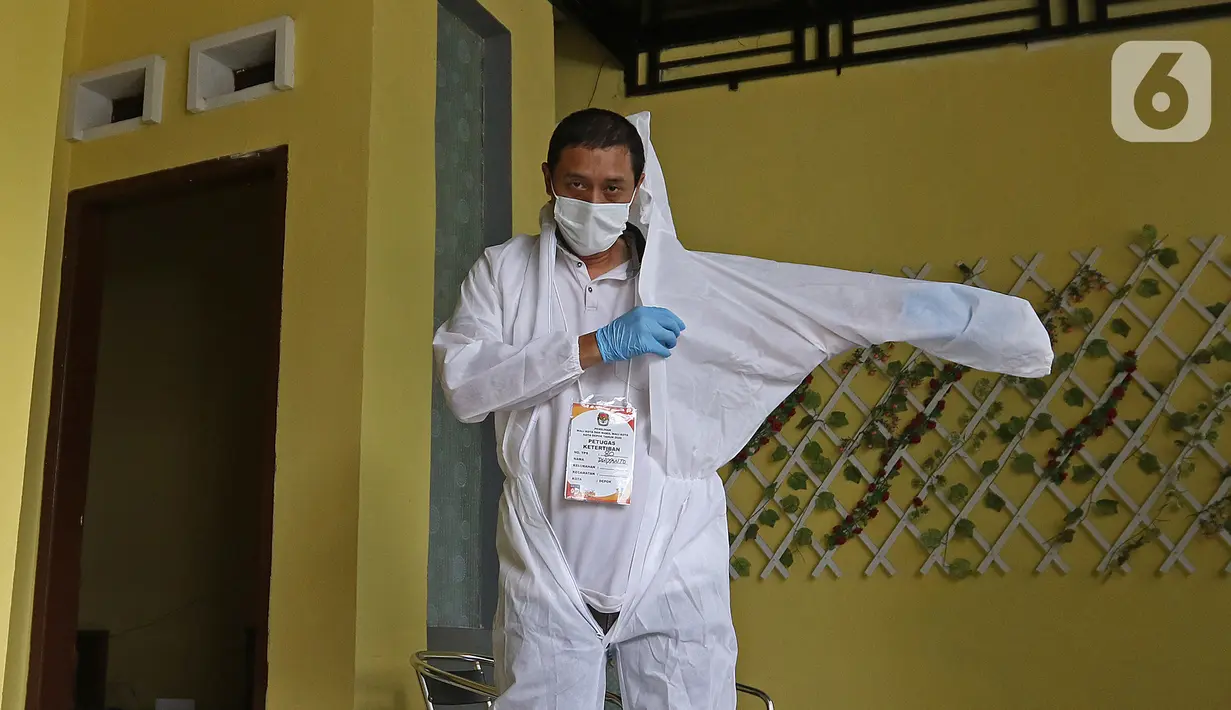 Petugas KPPS menggunakan hazmat sebelum menuju rumah pemilih di kawasan Depok, Rabu (9/12/2020). Petugas jemput bola atau mengambil suara dari warga yang diduga terpapar COVID-19 atau sedang menjalani isolasi mandiri di salah satu perumahan dalam Pilkada Depok 2020. (Liputan6.com/Herman Zakharia)